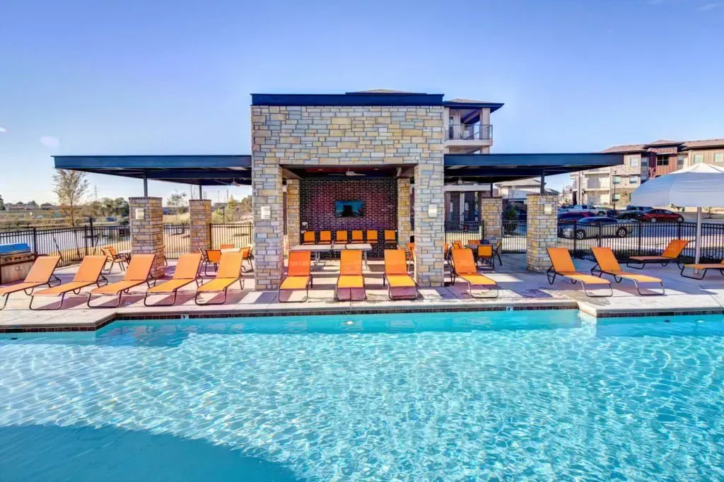 A large swimming pool surrounded by chairs and umbrellas.