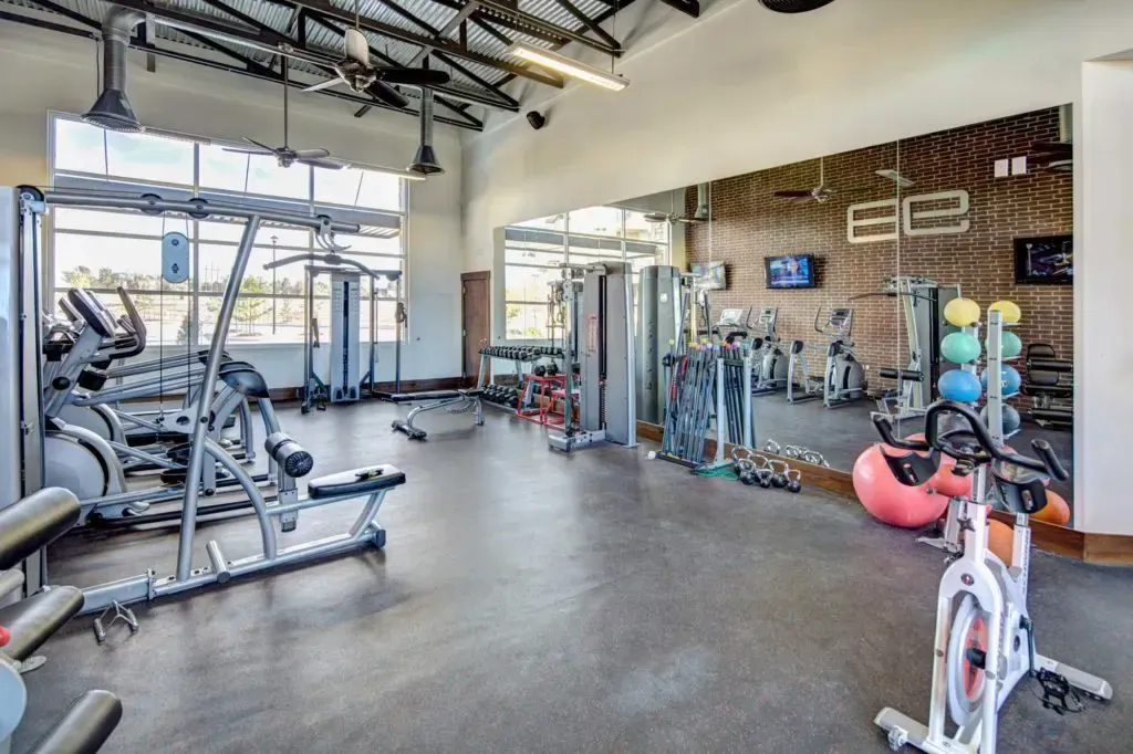 A large gym with a lot of equipment and a large mirror.