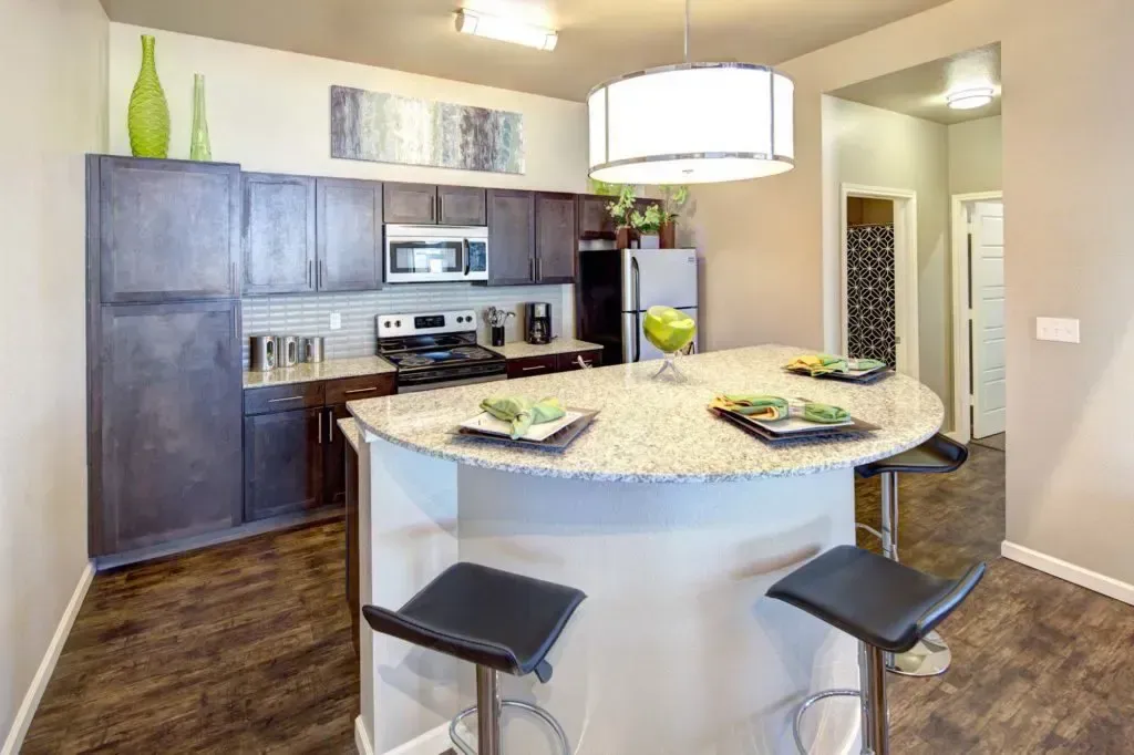 A kitchen with a large island and stools in it.