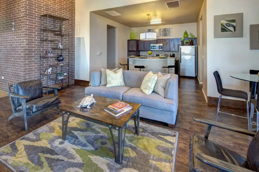 A living room with a couch , coffee table , chairs and a rug.