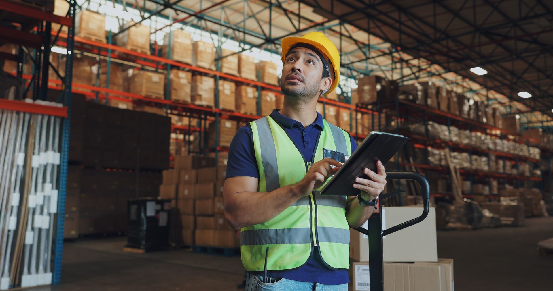 A man is using a tablet in a warehouse.