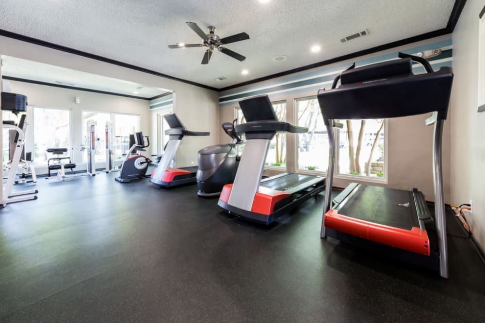 A gym with a lot of treadmills and a ceiling fan at Marquis at Legacy in Plano, TX.
