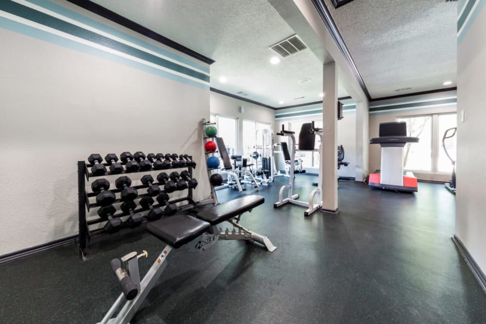 A fitness center with a treadmill, dumbbells, and a bench at Marquis at Legacy in Plano, TX.