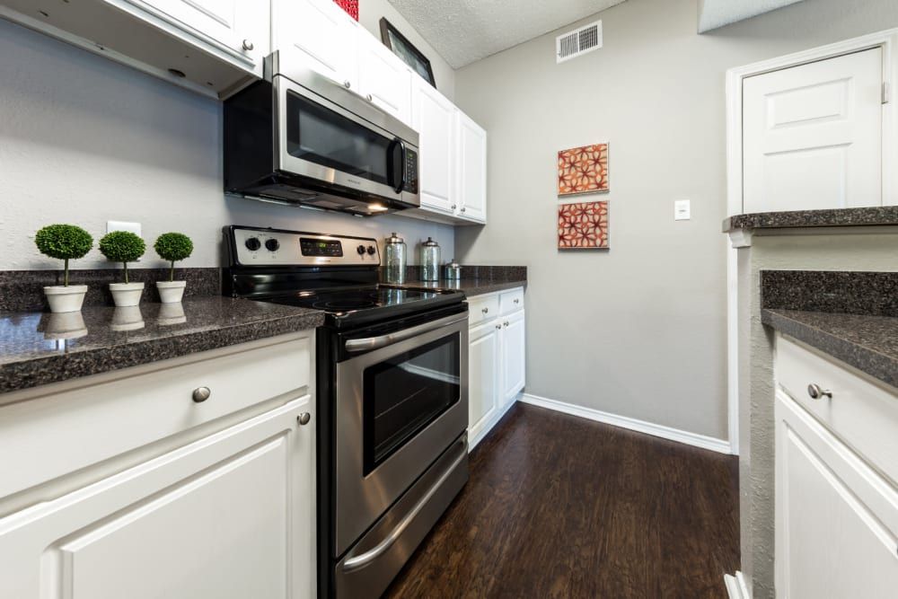 Apartment kitchen with stainless steel appliances and white cabinets at Marquis at Legacy in Plano, TX.