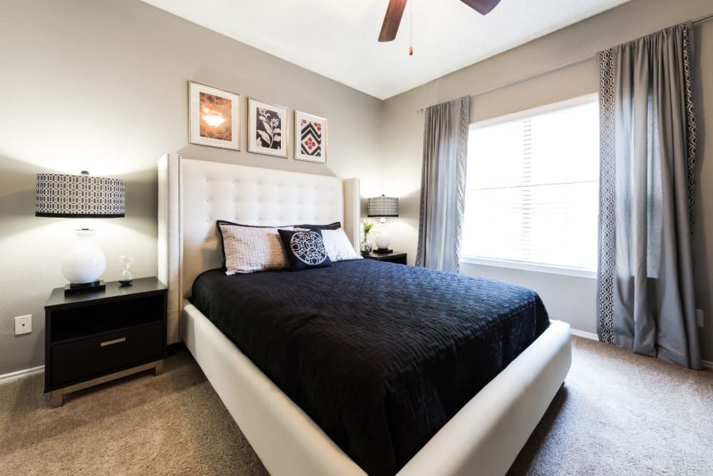 Apartment bedroom with a large bed and a ceiling fan at Marquis at Legacy in Plano, TX.