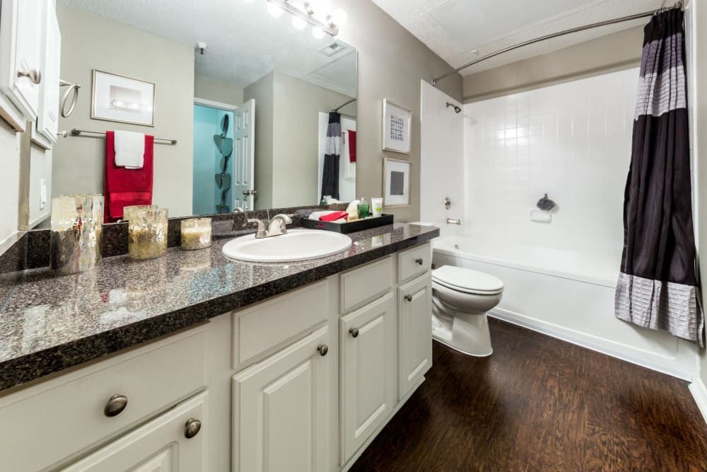 Apartment bathroom with a sink, toilet, bathtub, mirror, and plenty of countertop space at Marquis at Legacy in Plano, TX.