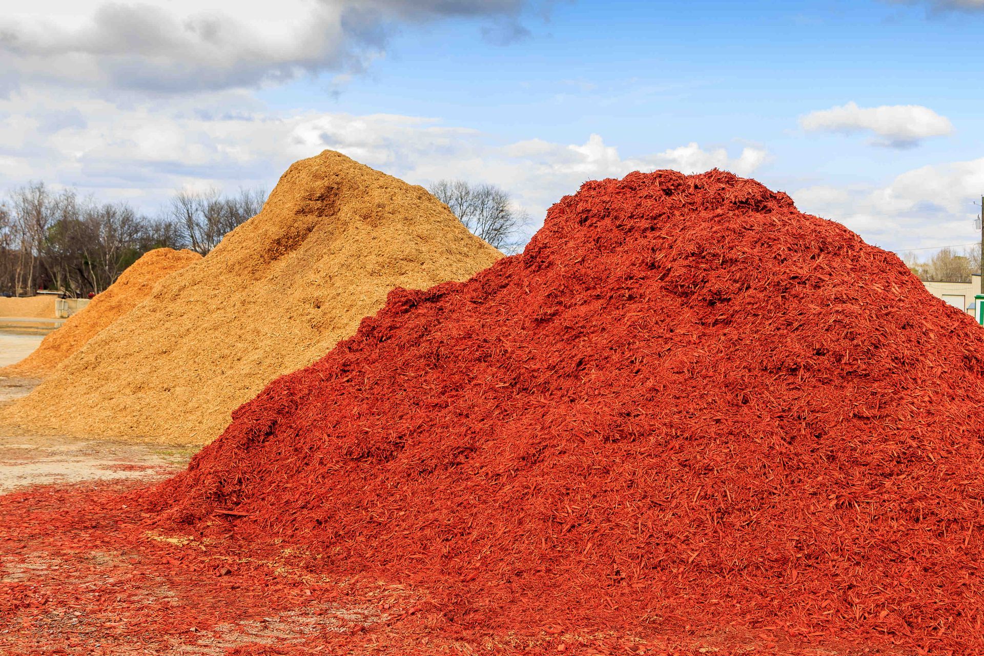 Two piles of mulch , one yellow and one red , are sitting on top of each other in a field.