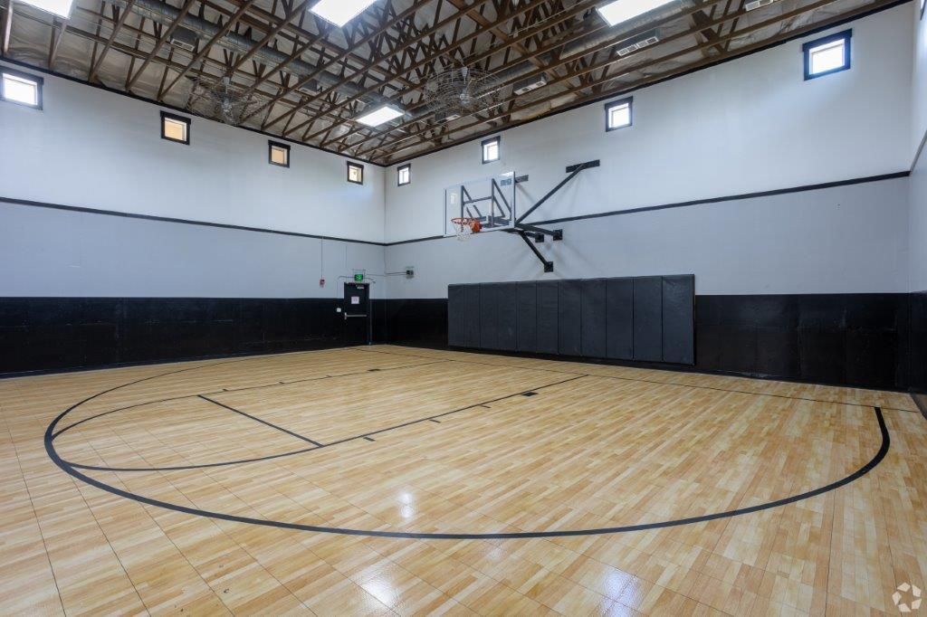 Modern indoor basketball court with hardwood floors and high ceilings at Hawks Ridge off campus student housing.