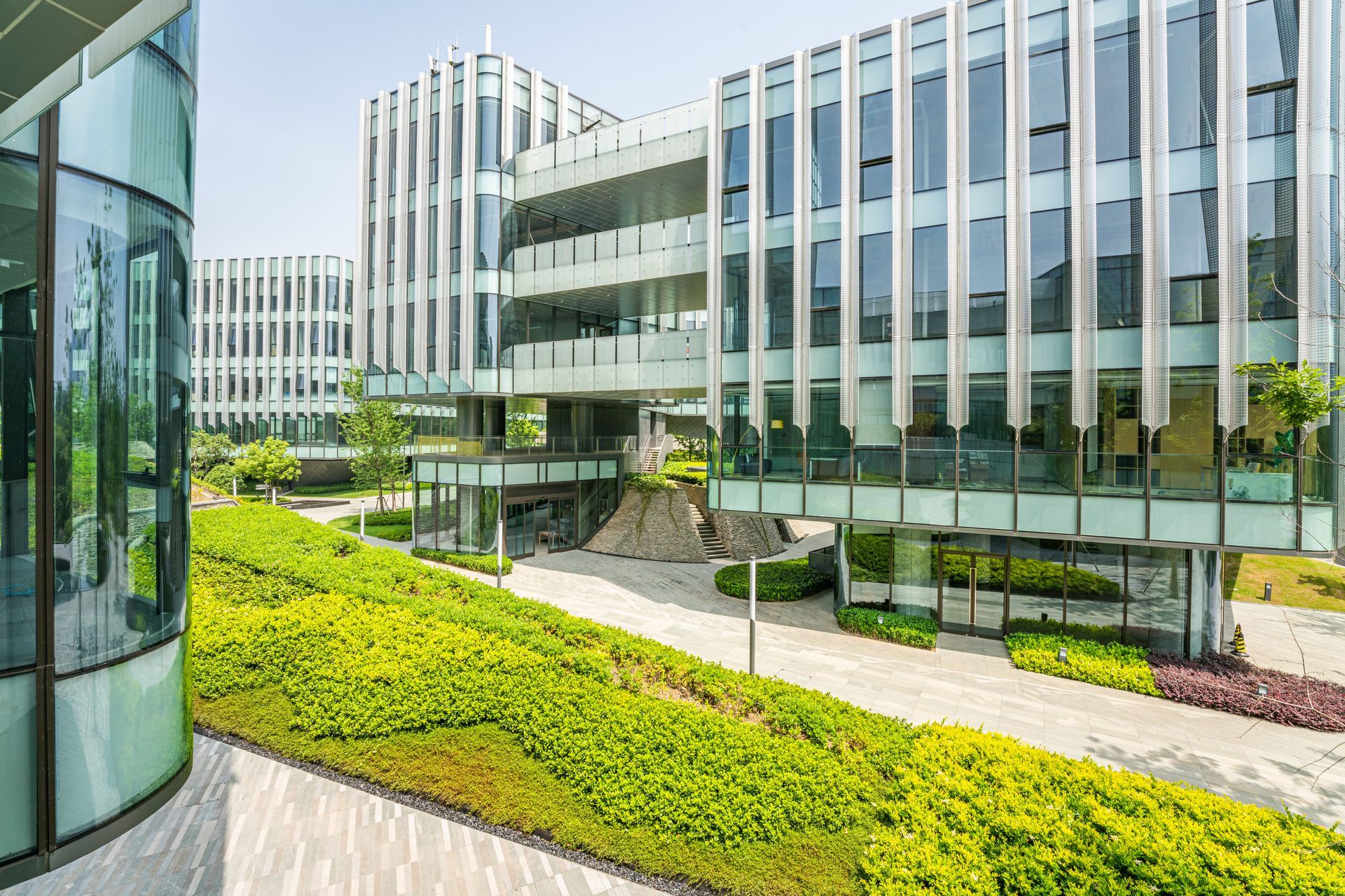 Modern office buildings with glass facade, surrounded by lush green landscaping on a sunny day. Modern office buildings with glass facade, surrounded by lush green landscaping on a sunny day.