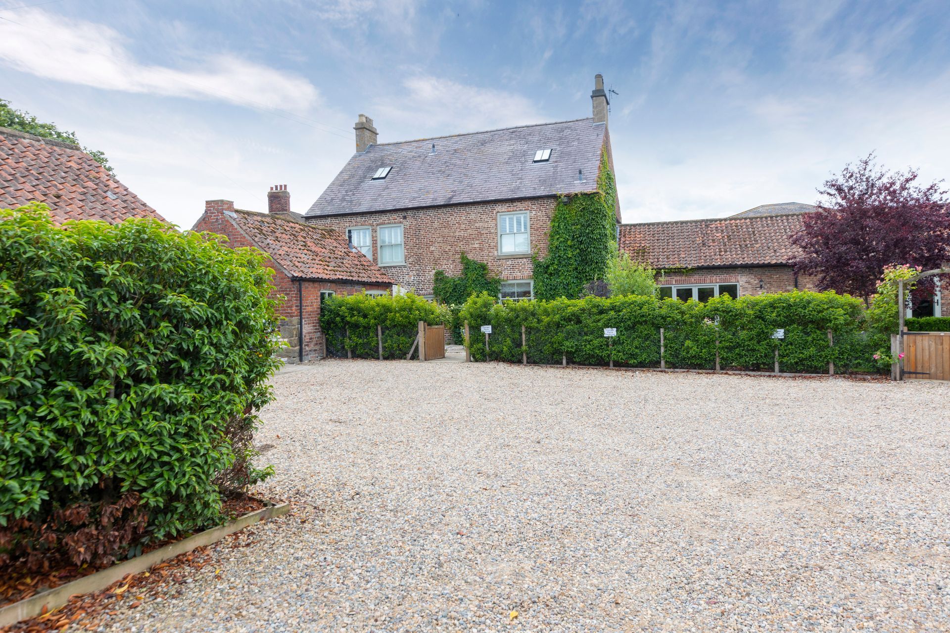 A large brick house with a gravel driveway in front of it.