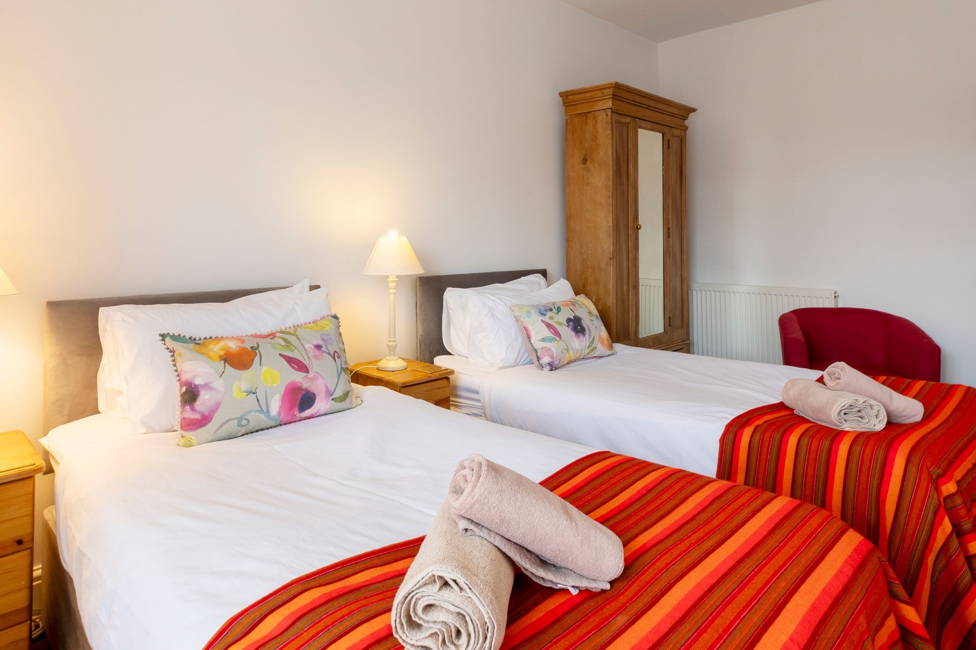 A bedroom with two beds , a mirror and a window.