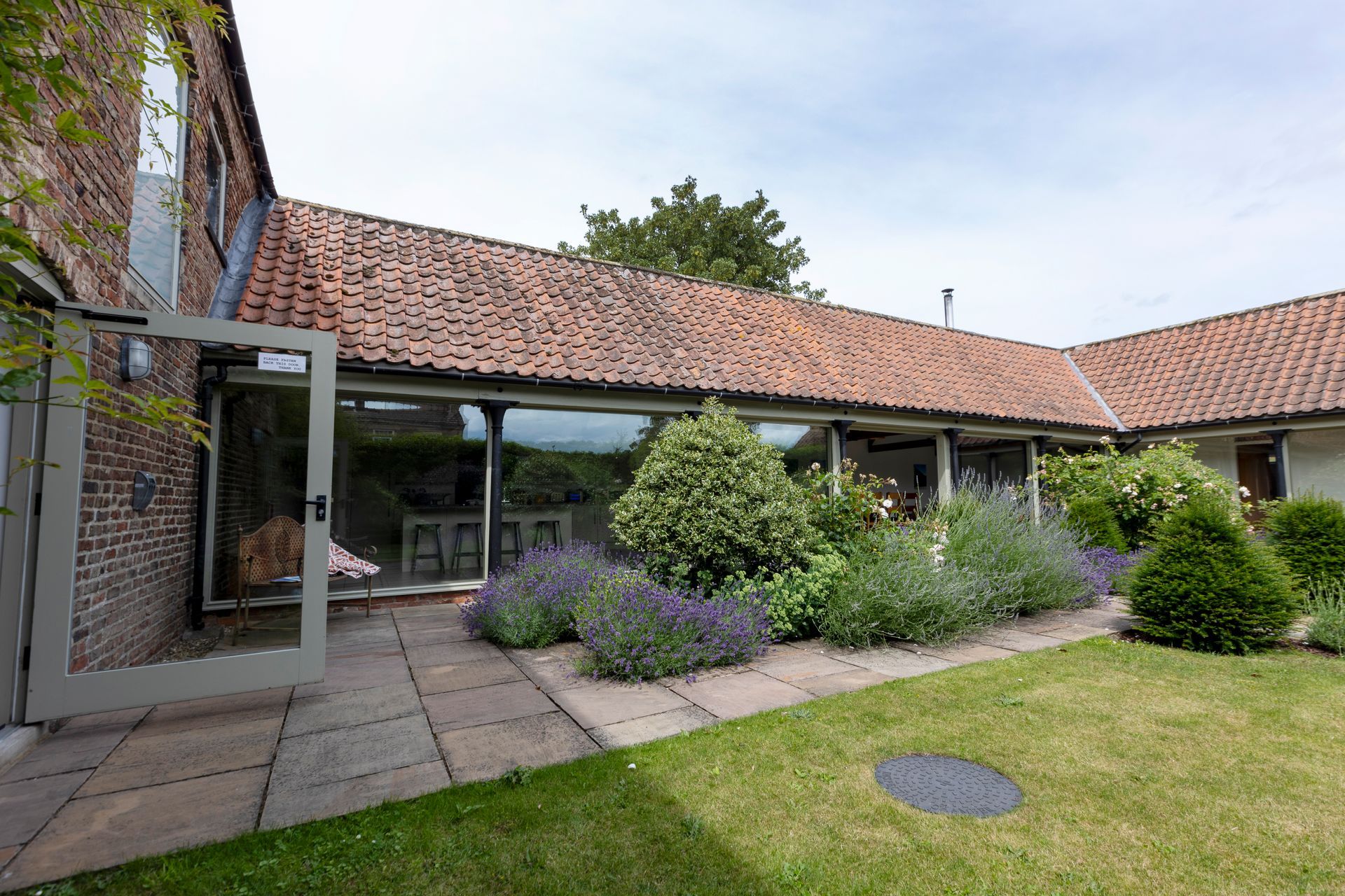 The Yard. A large brick building with a large glass door leading to a garden.