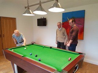 Three men are playing pool in a room with a pool table.