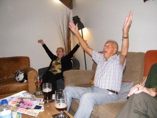 A group of people are sitting in a living room with their arms in the air
