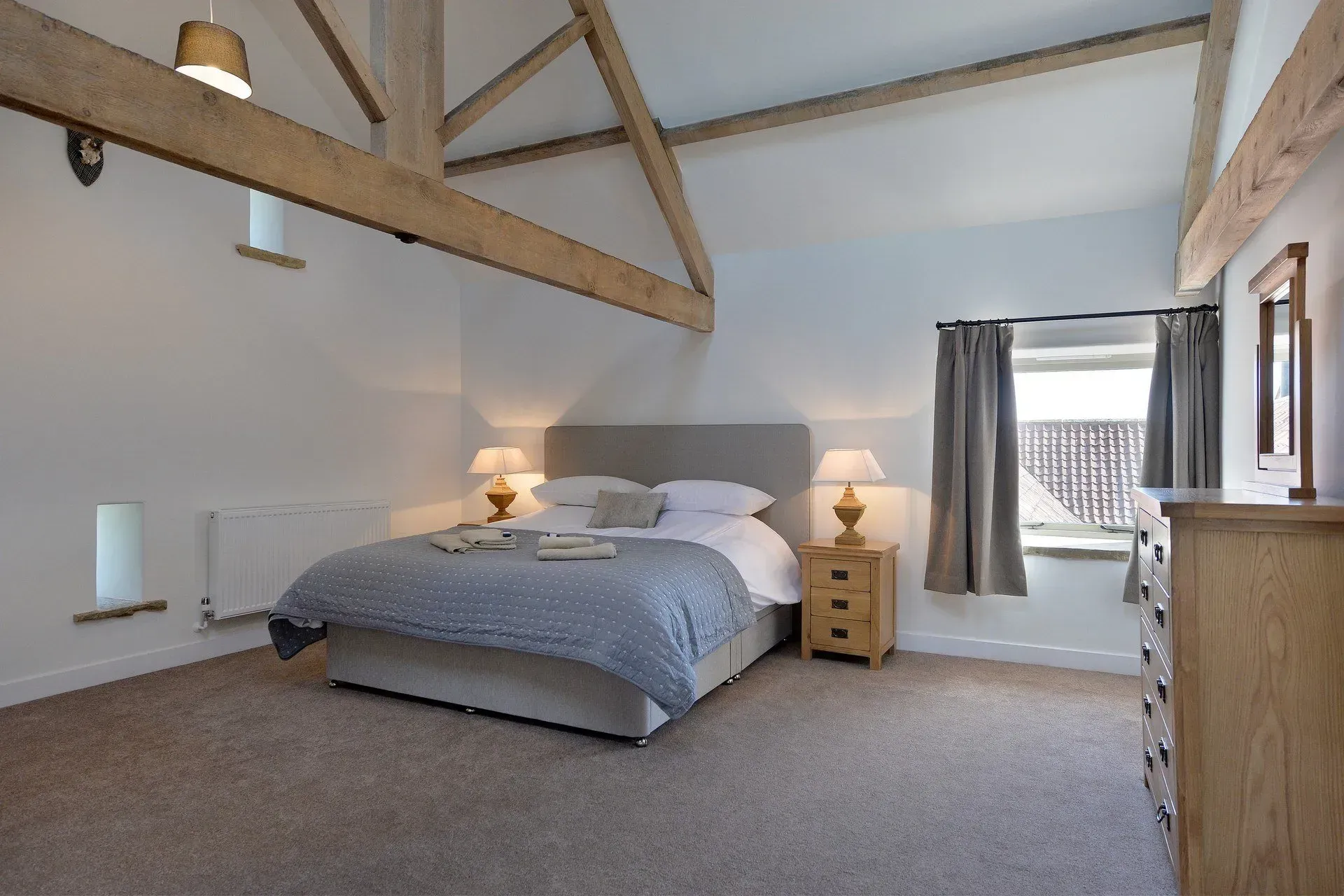 A bedroom with a king size bed , nightstand , chair and desk.