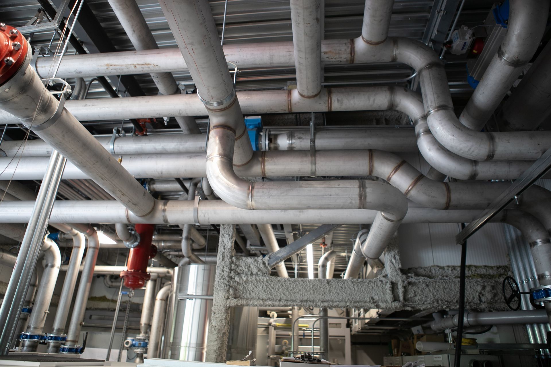 Réseau complexe de canalisations isolées en milieu industriel, avec vannes et raccords.