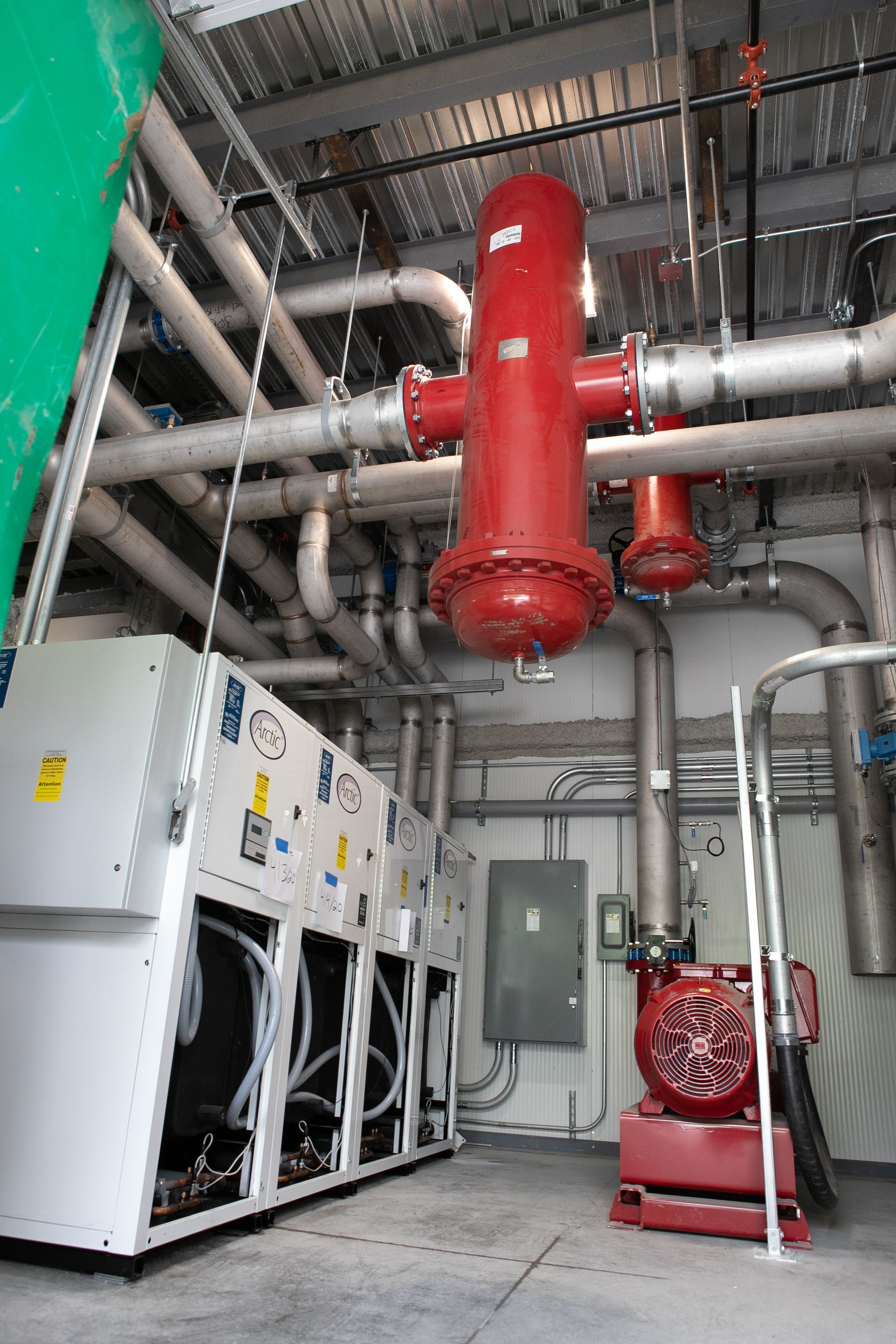Local technique CVC avec grand filtre rouge, tuyaux et panneaux électriques.
