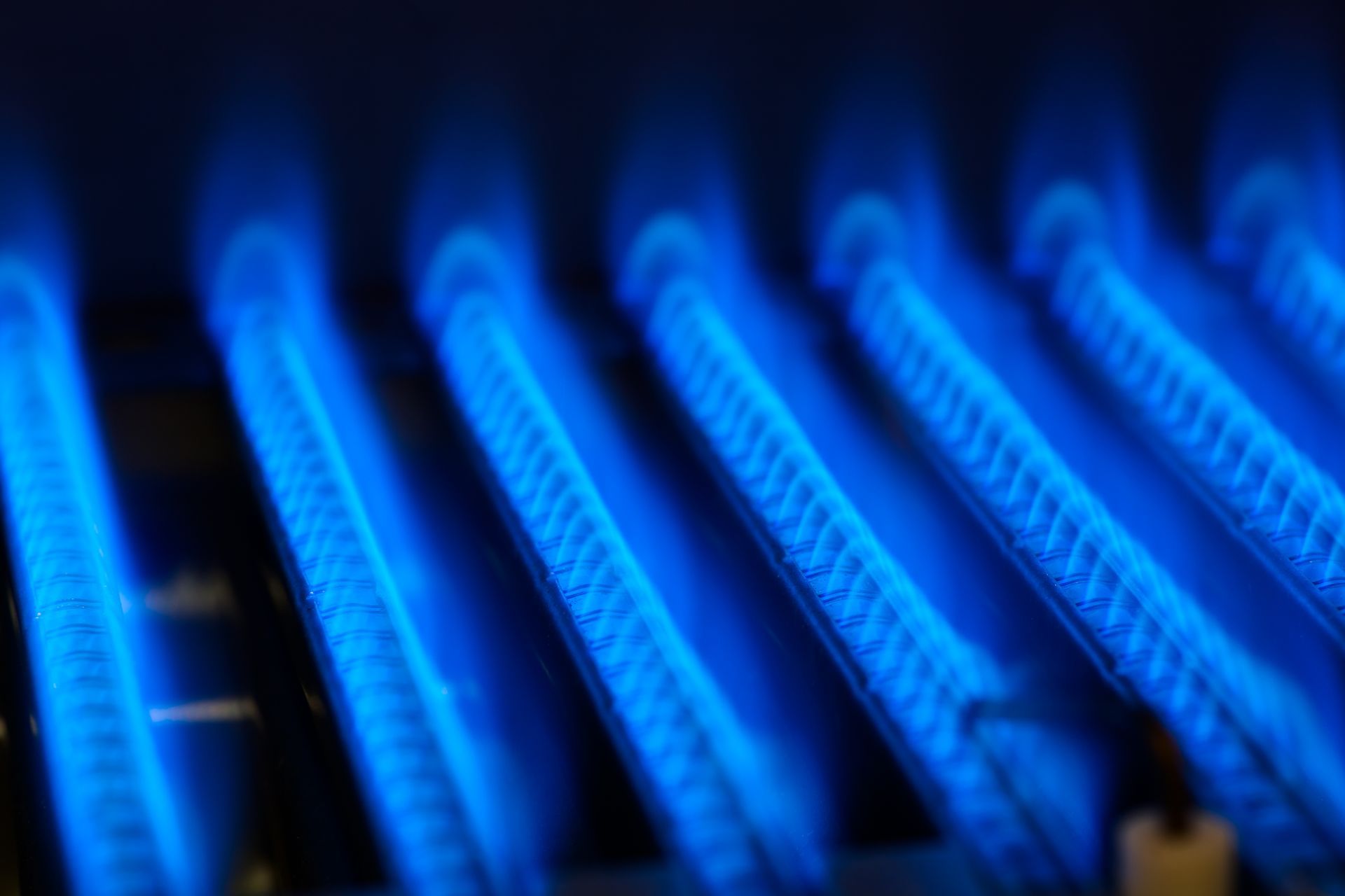 Flammes bleues d'un brûleur de fournaise à gaz, obliques, remplissant le cadre.