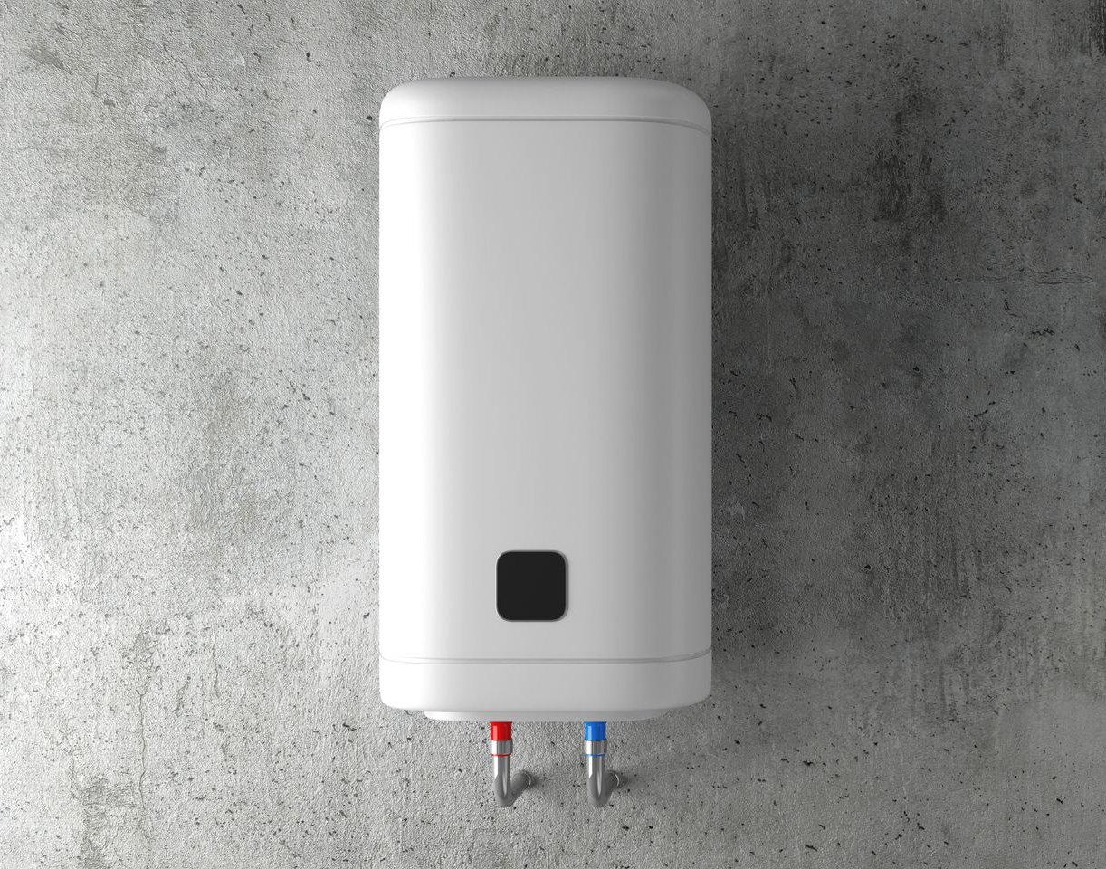 Chauffe-eau électrique blanc fixé sur un mur en béton gris, avec des tuyaux rouges et bleus visibles.
