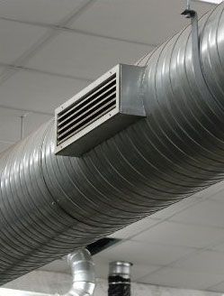 Conduit de ventilation argenté avec grille d'aération intégrée, suspendu au plafond.