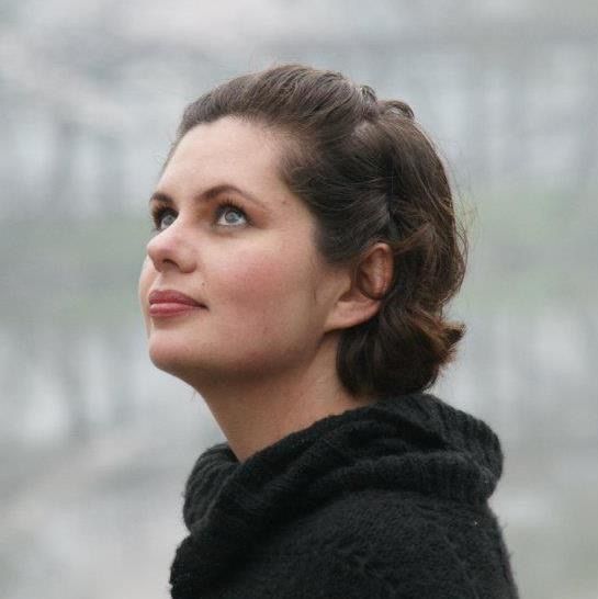 A woman in a black sweater is looking up at the sky