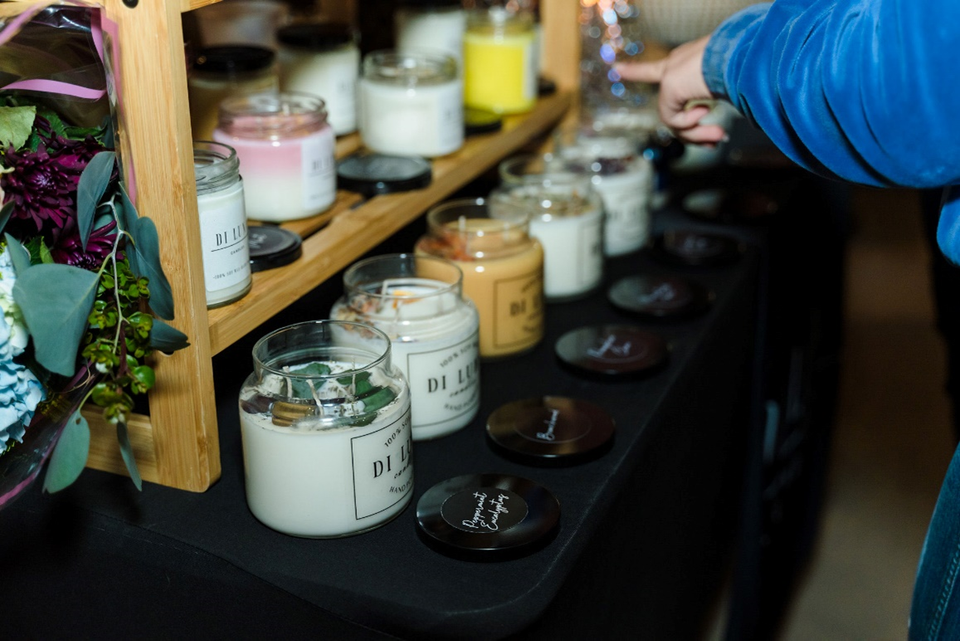 A person is standing in front of a table filled with candles.