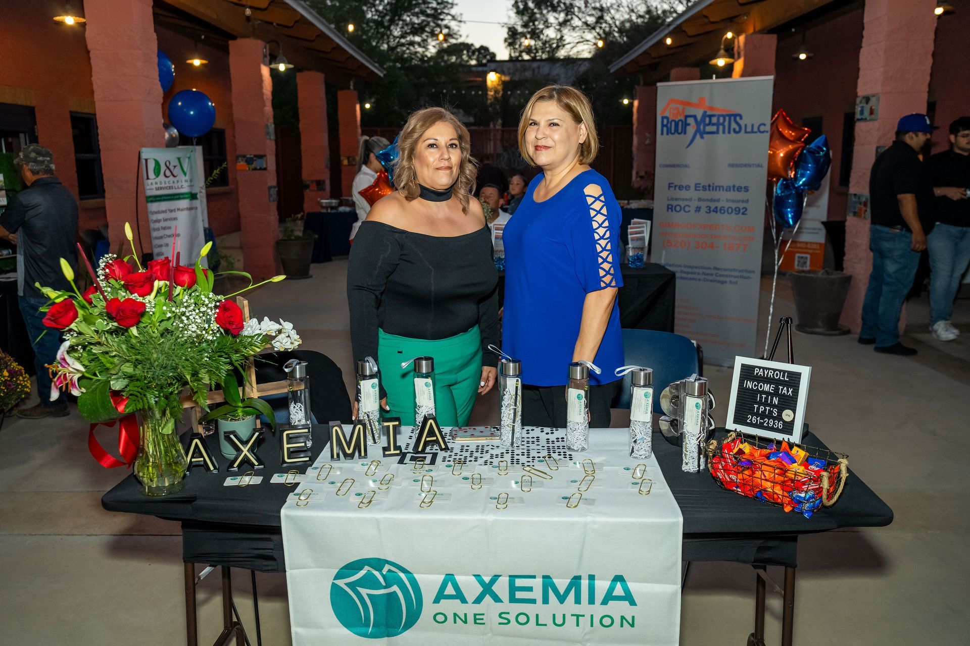 Two women are standing in front of a table that says axemia one solution.
