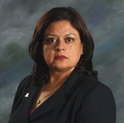 A woman wearing a black jacket and a necklace is looking at the camera