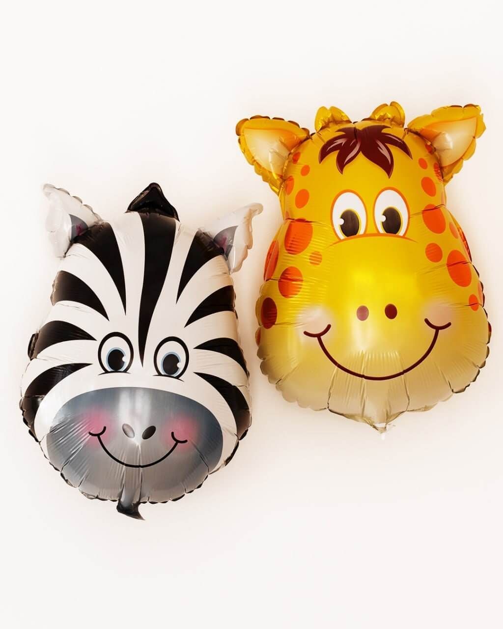 Un globo de cebra y una jirafa están sentados uno al lado del otro sobre una superficie blanca.