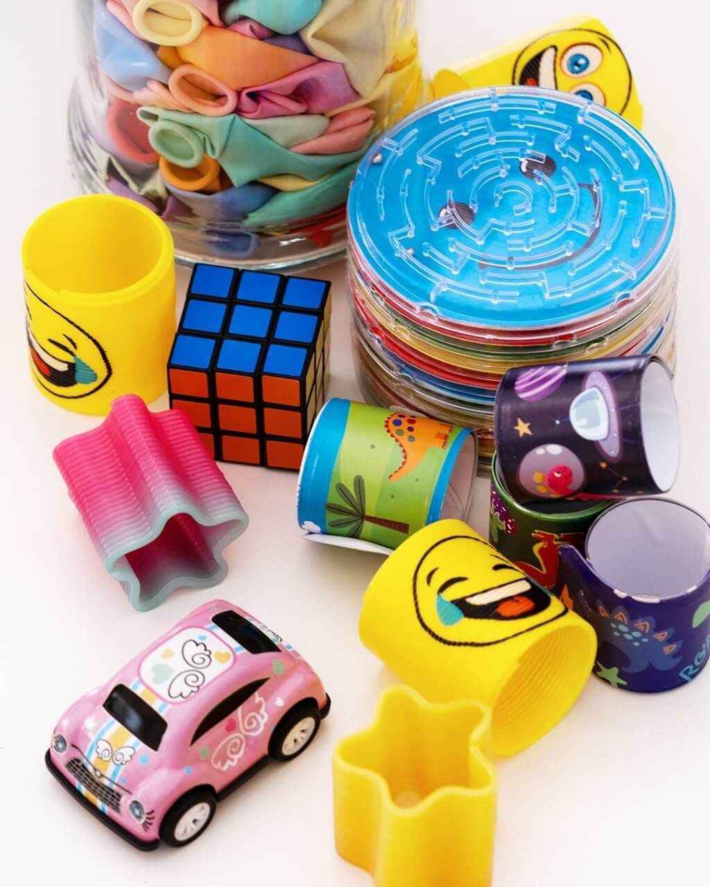 Un montón de juguetes que incluyen un coche rosa y un cubo de Rubik.