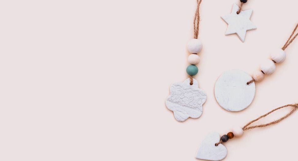 Un grupo de adornos de arcilla colgando de una cuerda sobre un fondo blanco.