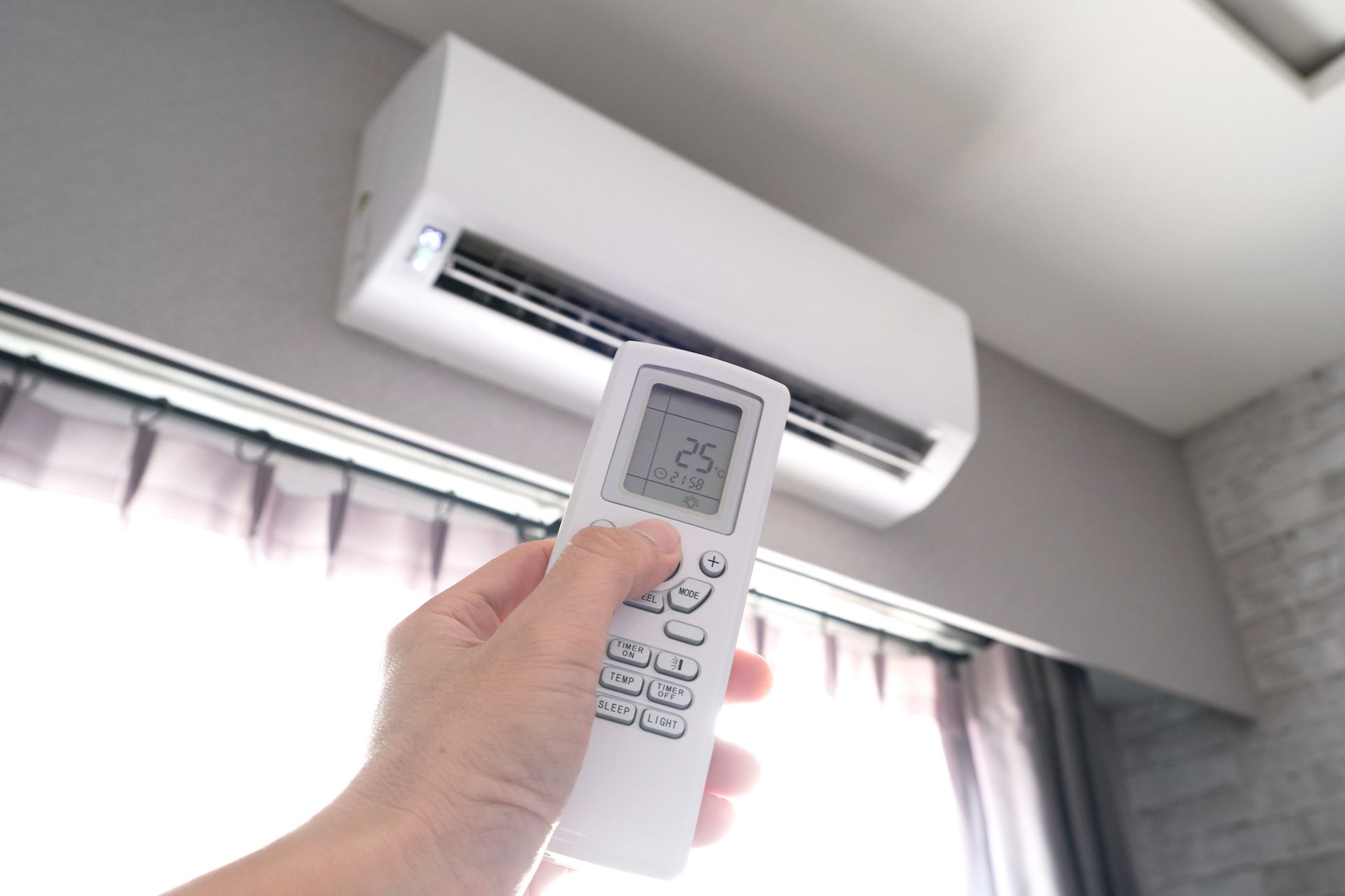 Man's hand using remote control opens the air conditioner.
