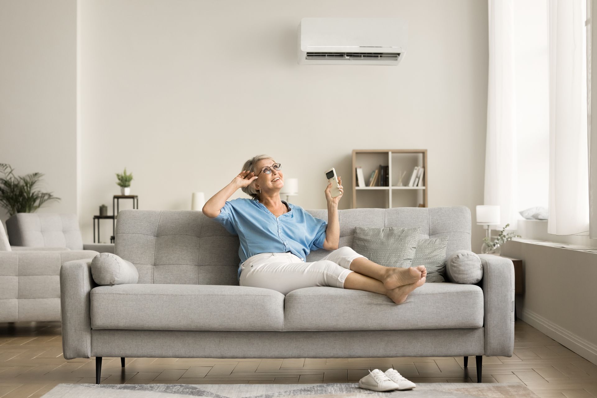 Happy relaxed senior lady holding AC remote control.