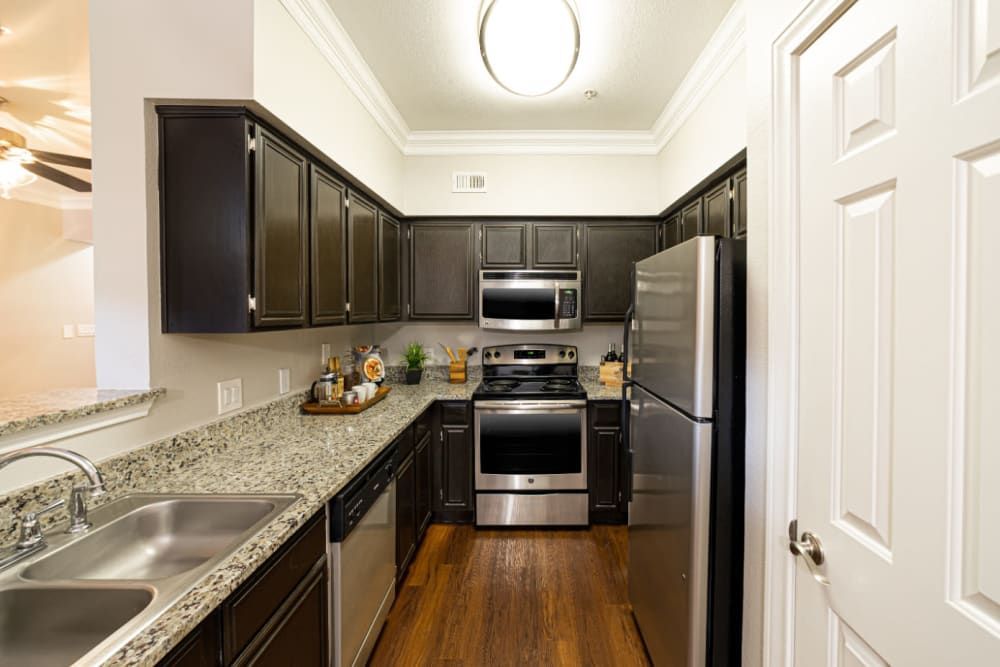 a kitchen with stainless steel appliances and granite counter tops at Marquis at Great Hills in Austin, TX.