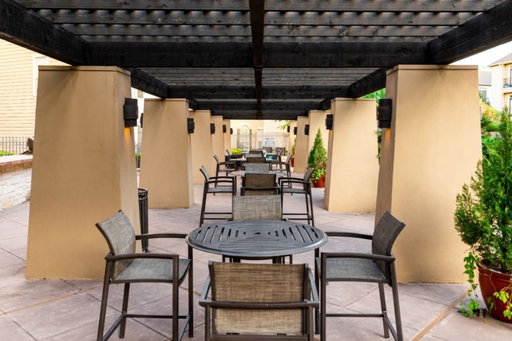 a patio with a table and chairs under a pergola at Marquis at Great Hills in Austin, TX.