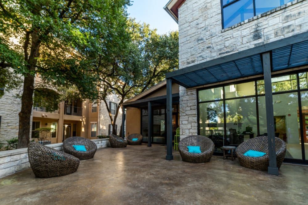 a patio with chairs and a pergola in front of a building at Marquis at Great Hills in Austin, TX.