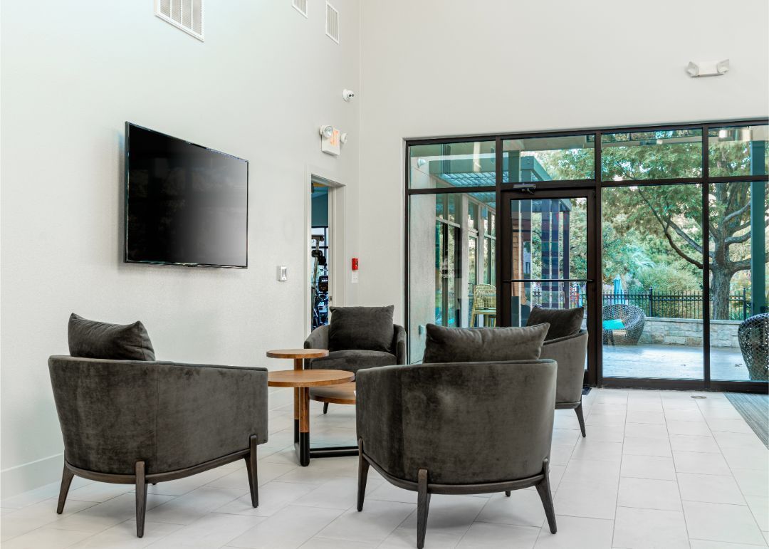 a living room with chairs, a table, and a flat-screen tv at Marquis at Great Hills in Austin, TX.