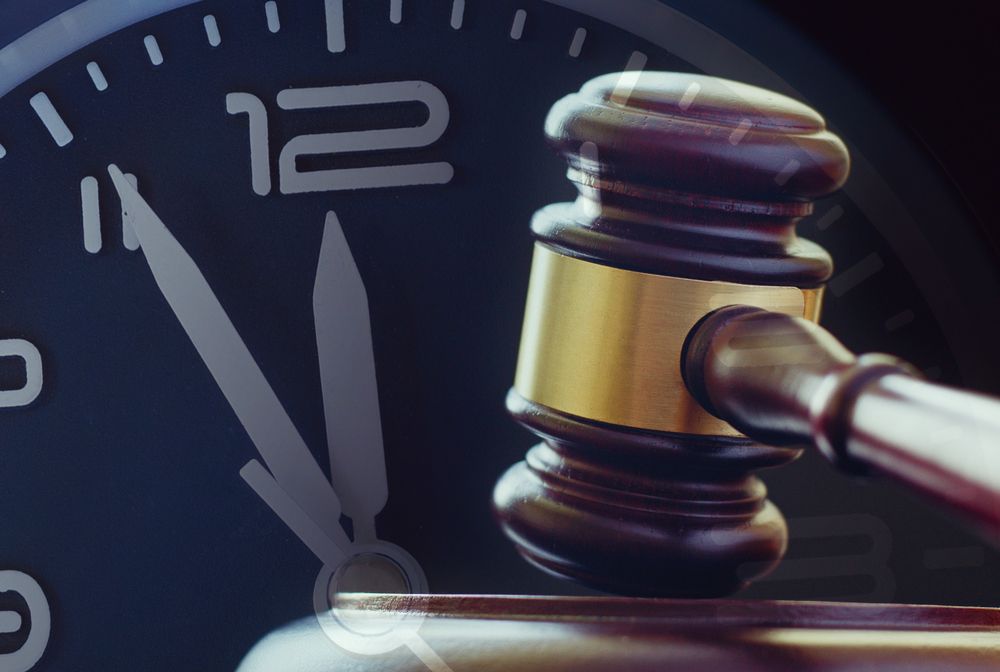 A judge 's gavel is sitting in front of a clock that says 12