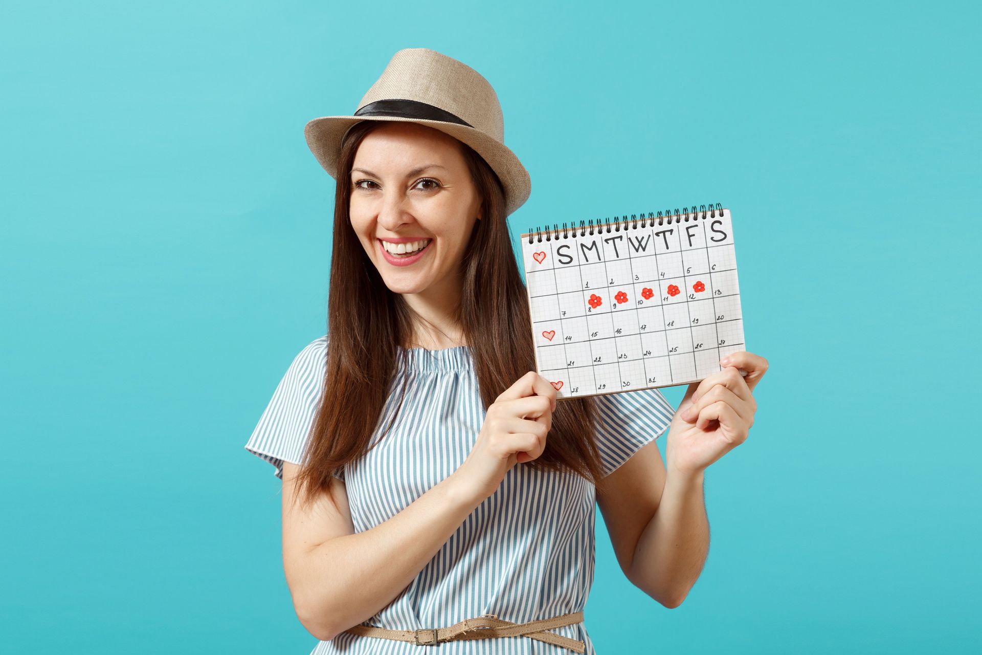 Woman in hat holding calendar with marked dates, smiling against a blue backdrop.