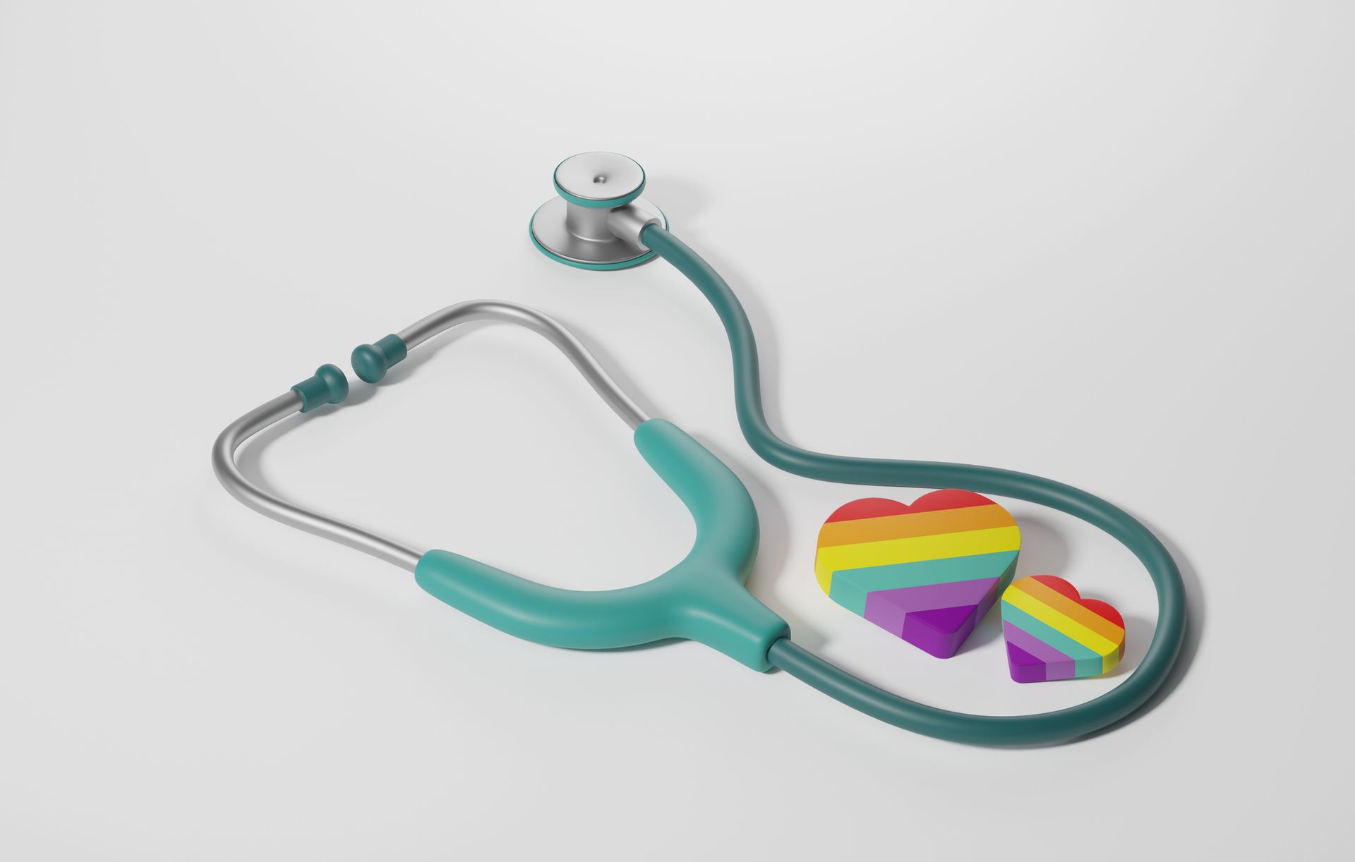 A stethoscope and two rainbow-colored hearts on a white surface, representing LGBTQ+ healthcare.