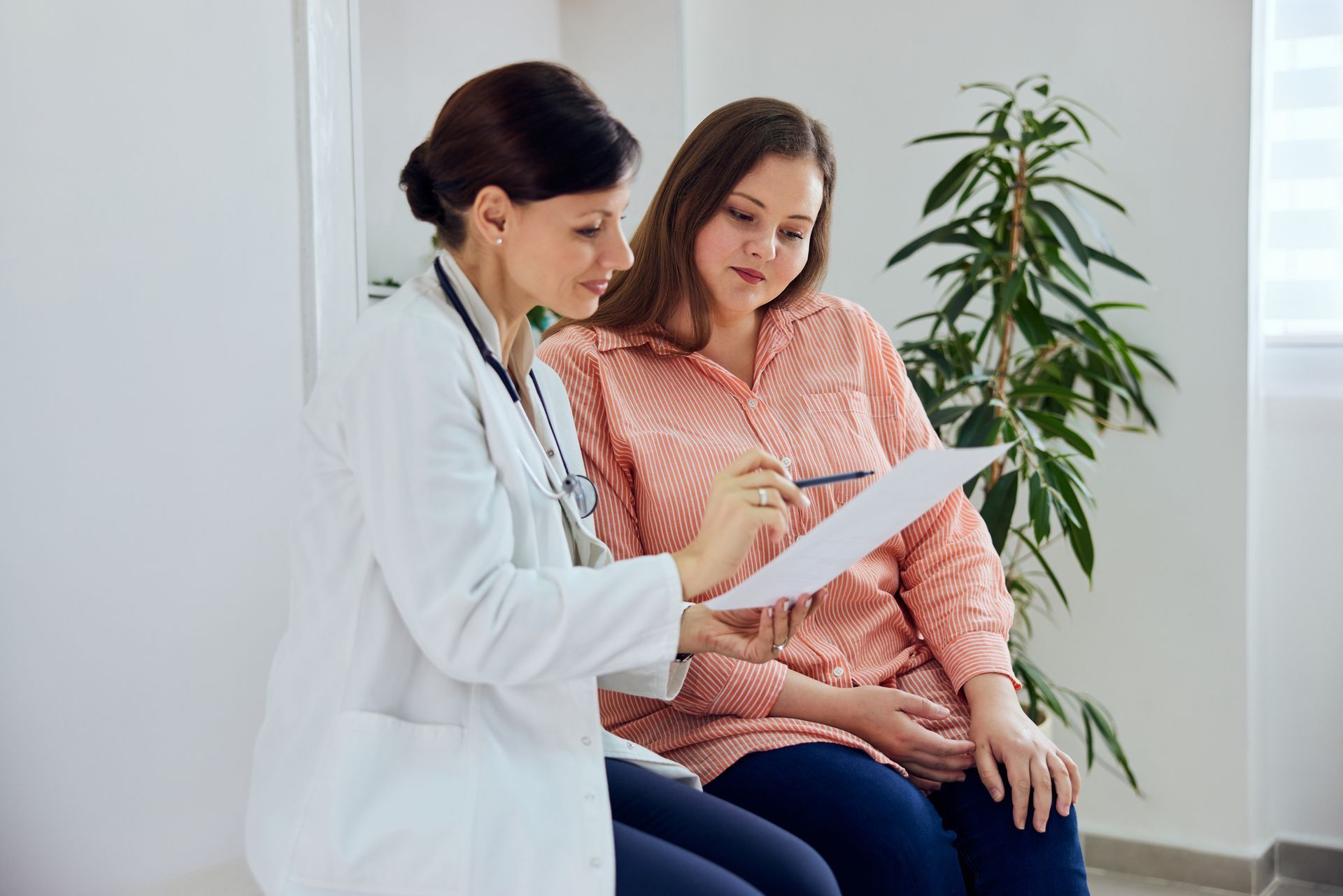 Doctor reviewing papers with patient in a bright room with plant.