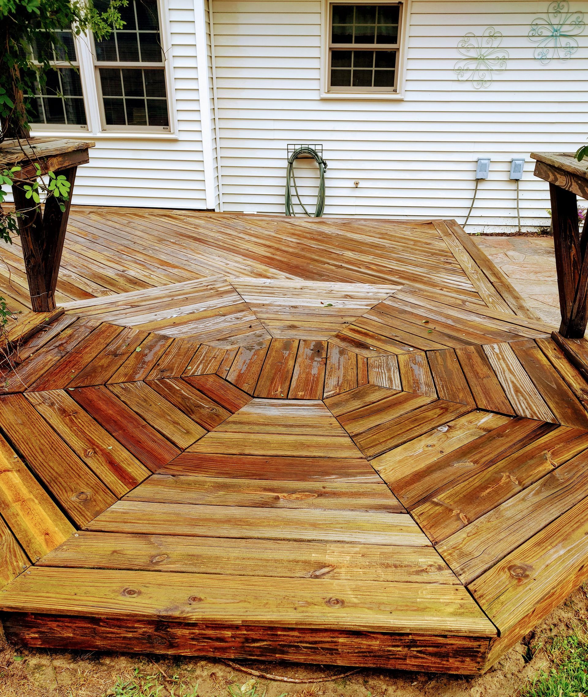 Wooden, octagonal-shaped deck in front of a white house.
