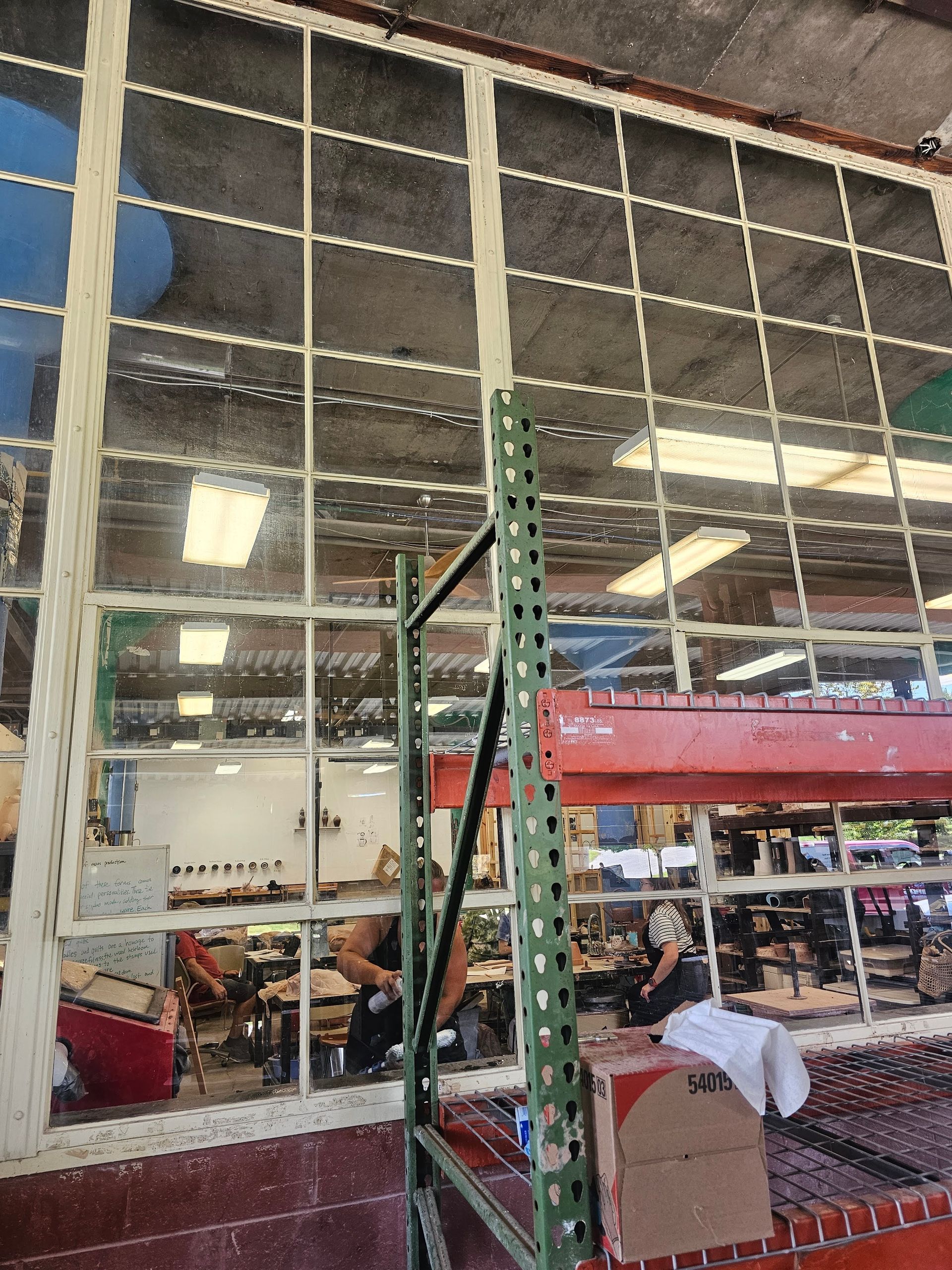 Large warehouse windows with visible shelving and people working in the background.