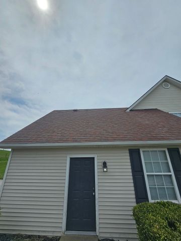 Beige house with a brown roof and a dark door, beneath a cloudy sky.