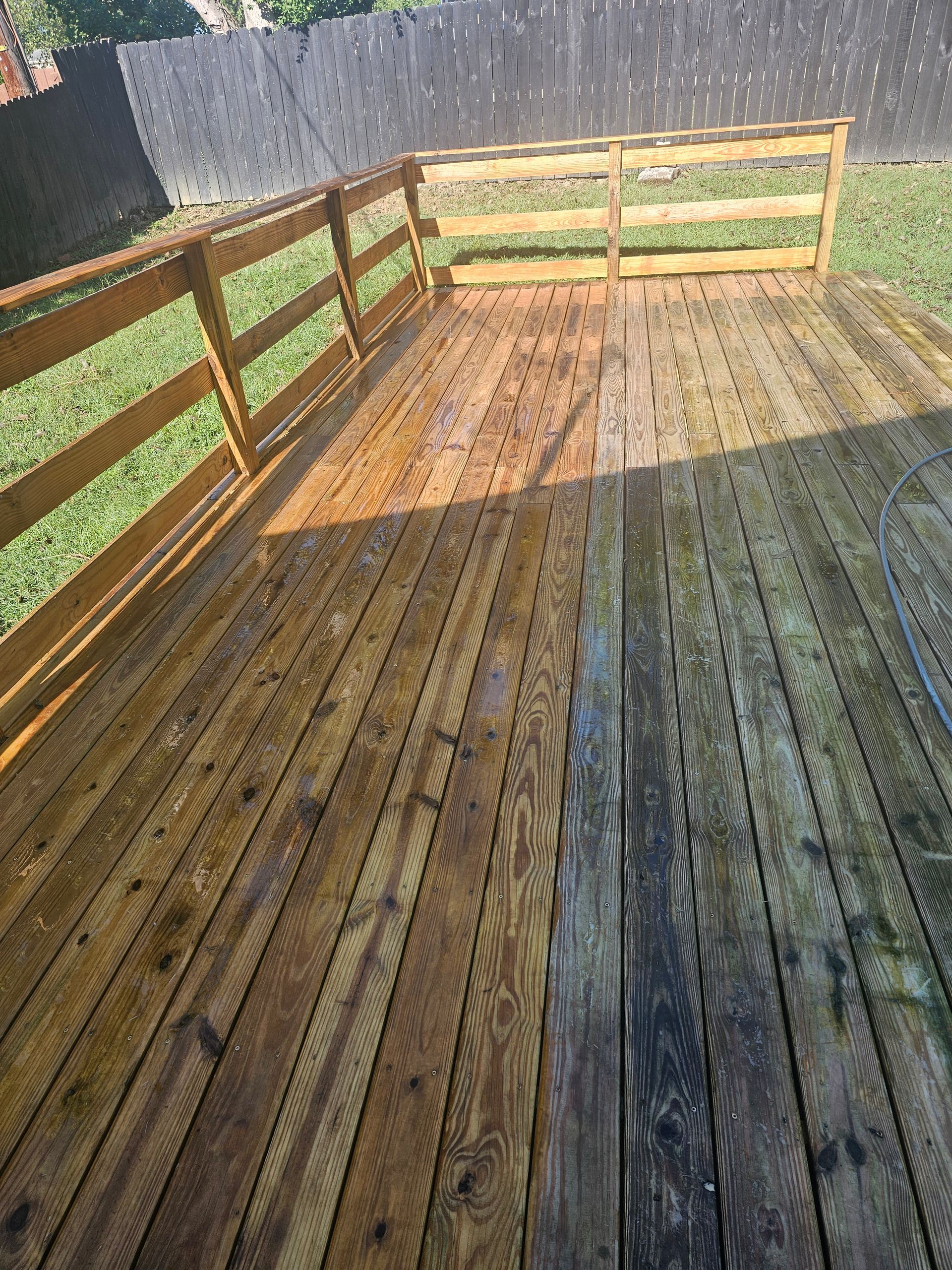 Person power washing a driveway in front of a house. Sunlight.