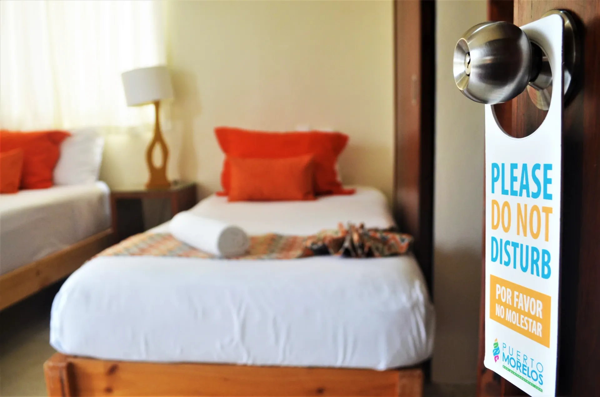 Dormitorio con dos camas, almohadas naranjas y un cartel de 