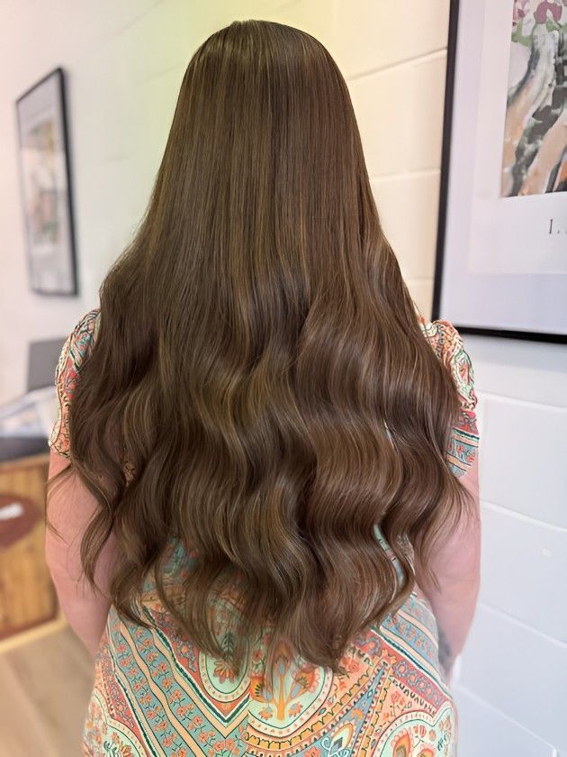 A Woman With Long Brown Hair is Standing in Front of a Wall — Atelier Of Hair in Grafton, NSW