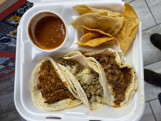 A styrofoam container filled with tacos and tortilla chips.