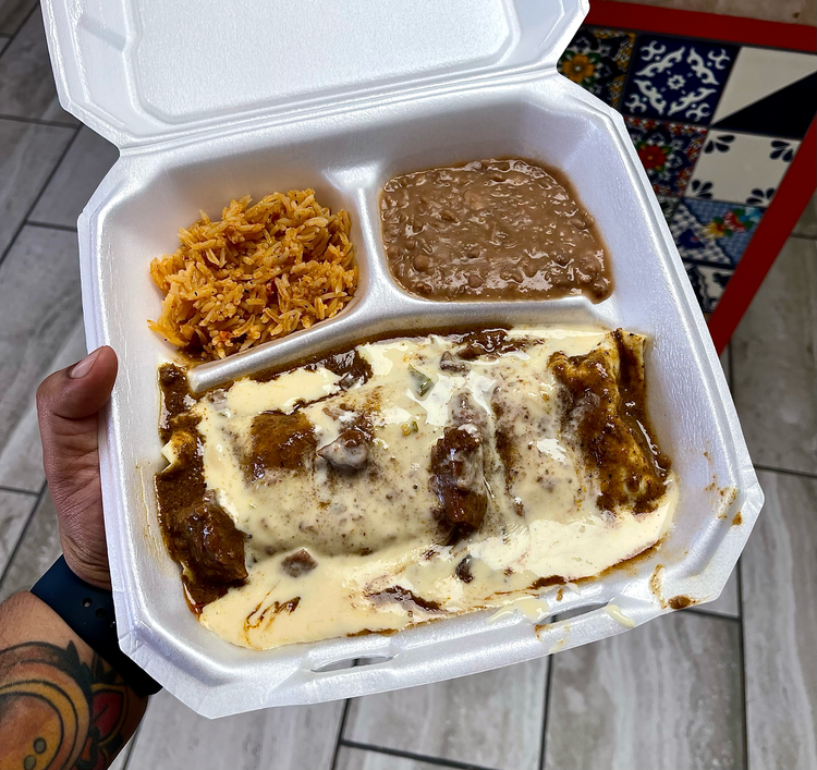 A person is holding a styrofoam container filled with food