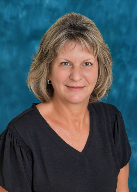 Studio portrait of a smiling woman in a black top against a blue background